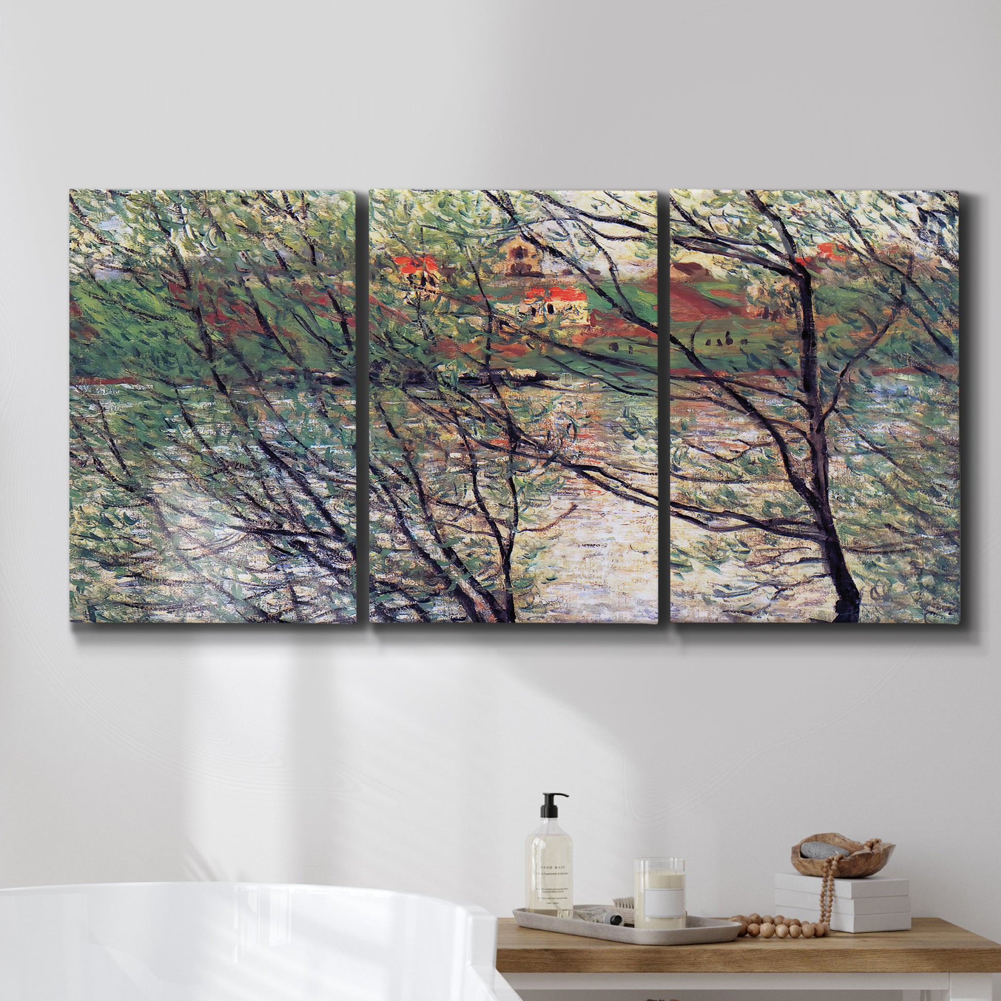 Three-panel canvas wall art featuring riverside park with figures and trees, displayed in a bathroom above a bathtub.