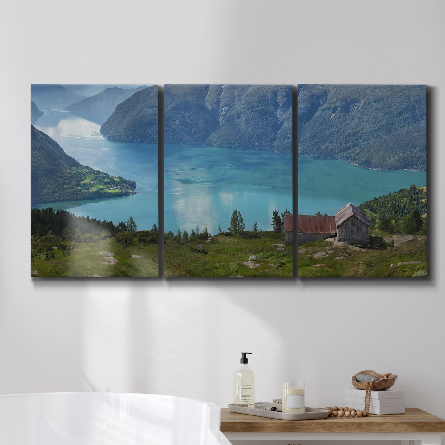 Three-panel canvas wall art featuring symmetrical water reflections with trees, displayed in a bathroom above a bathtub.