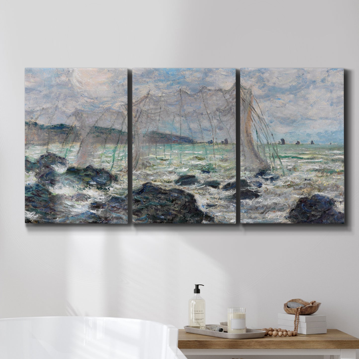 Three-panel canvas wall art featuring rough seas along rocky coast, displayed in a bathroom above a bathtub.