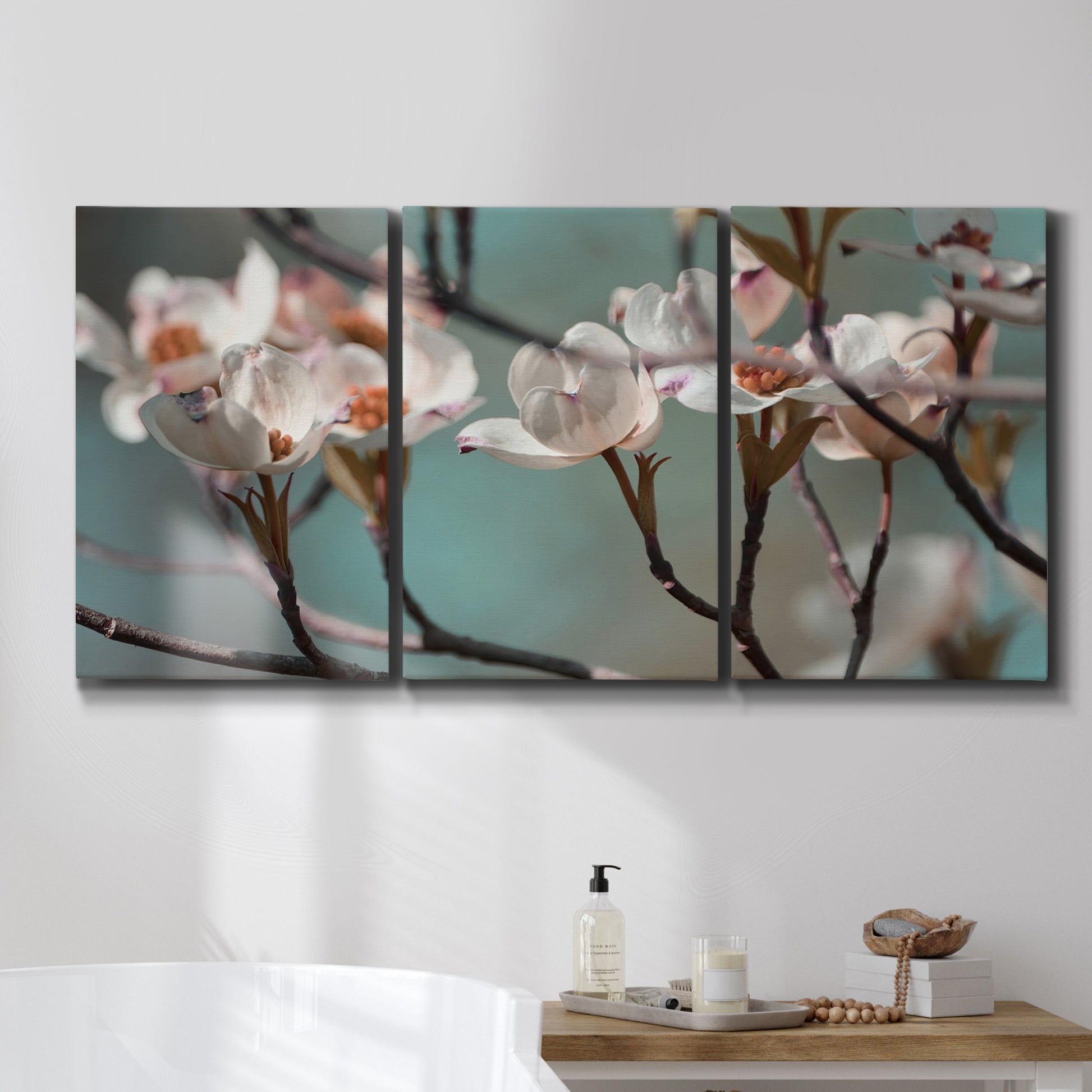 Three-panel canvas wall art featuring dogwood blossoms in spring photograph, displayed in a bathroom above a bathtub.