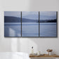 Three-panel canvas wall art featuring calm blue water landscape, displayed in a bathroom above a bathtub.