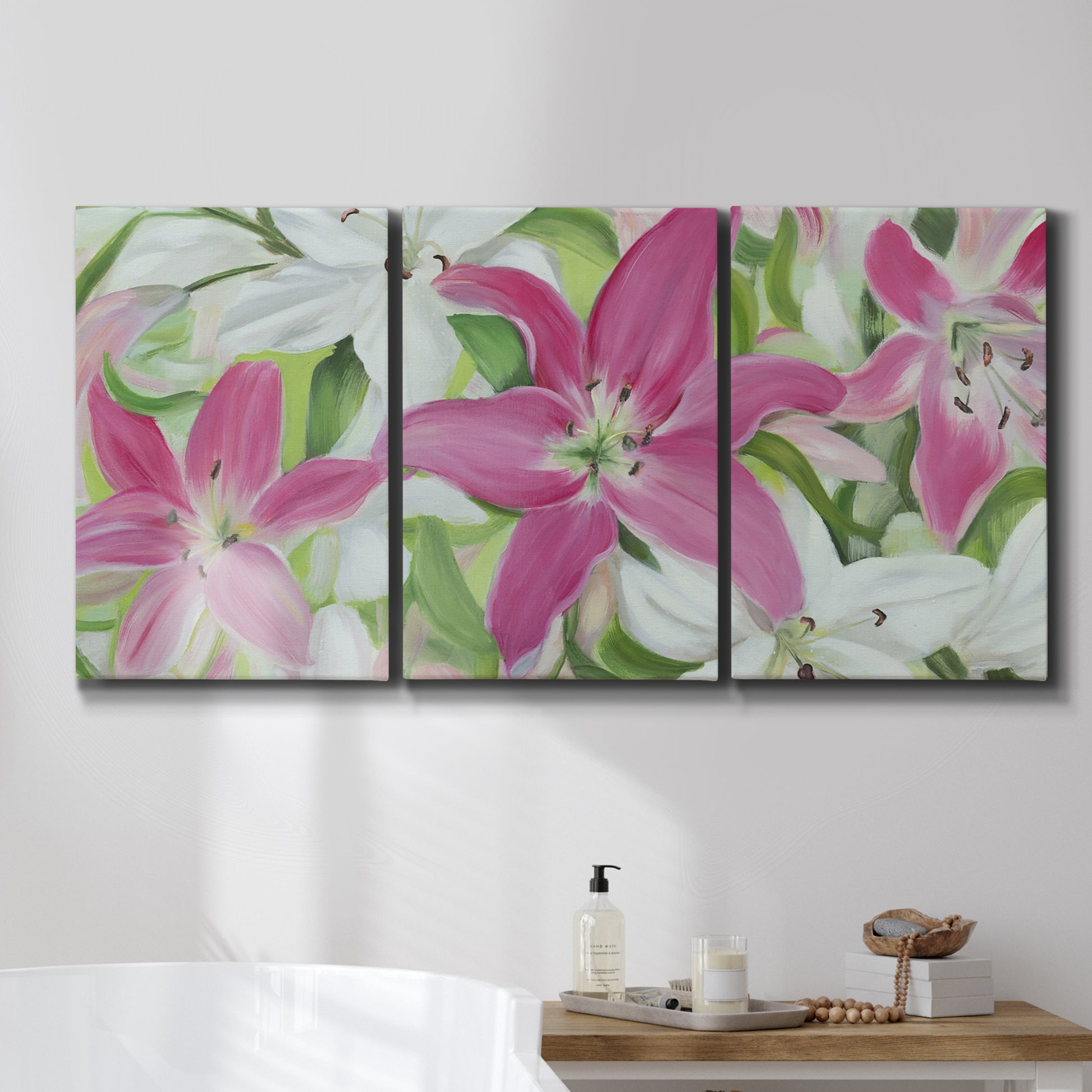 Three-panel canvas wall art featuring pink and white lilies in bloom, displayed in a bathroom above a bathtub.
