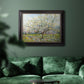 Impressionist white-blossomed orchard landscape by Vincent van Gogh in an ornate black frame with gilded inner detail displayed in a dark-toned interior setting.