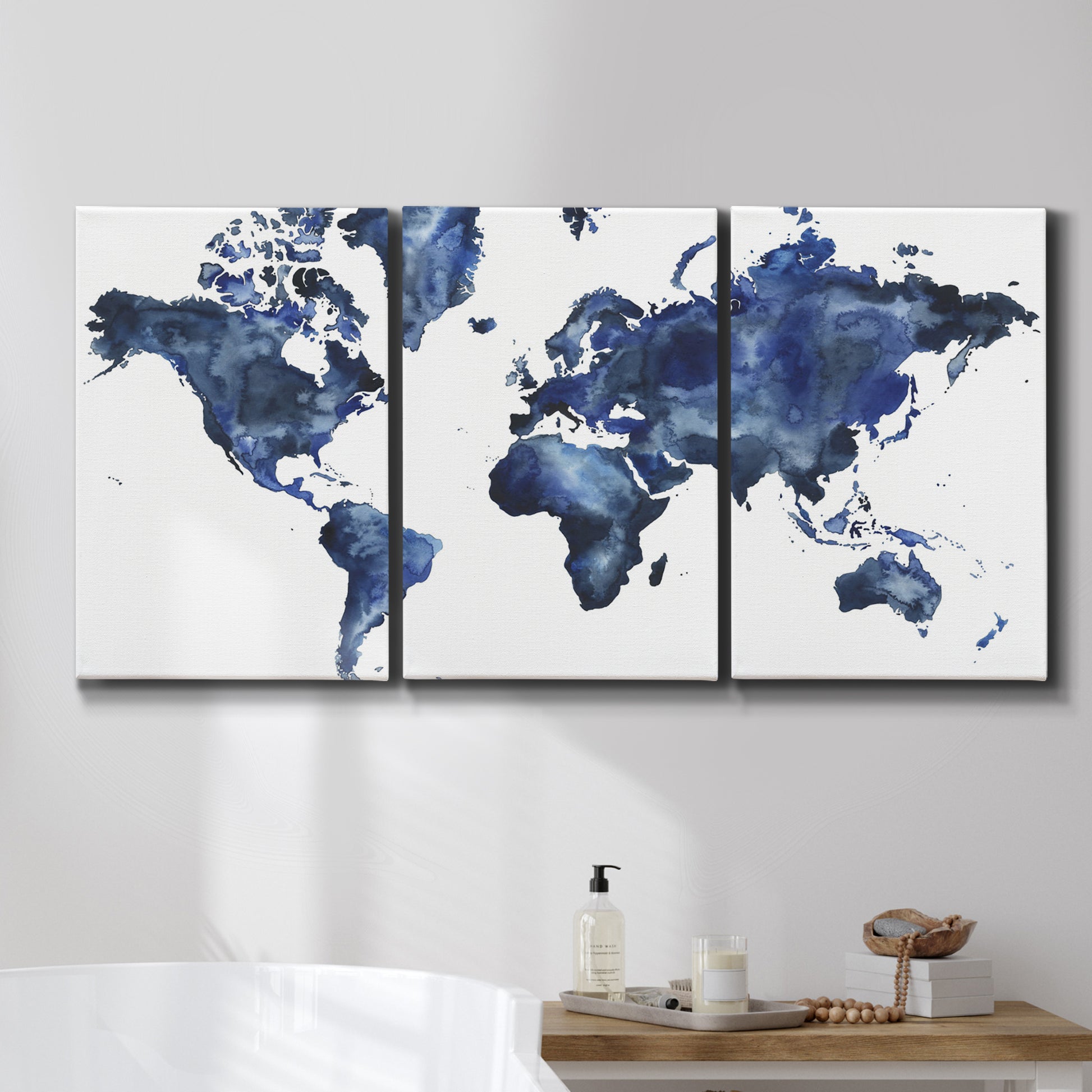 Three-panel canvas wall art featuring world map with water motif, displayed in a bathroom above a bathtub.