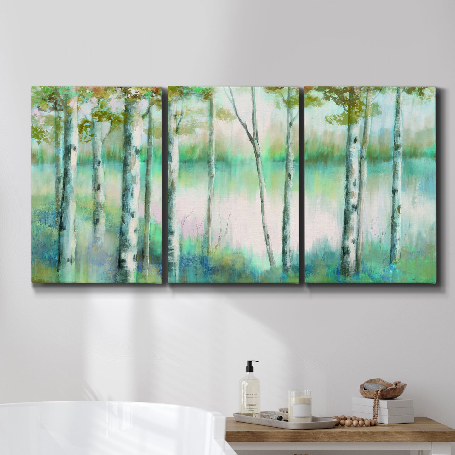 Three-panel canvas wall art featuring calm lake framed by aspen trees, displayed in a bathroom above a bathtub.
