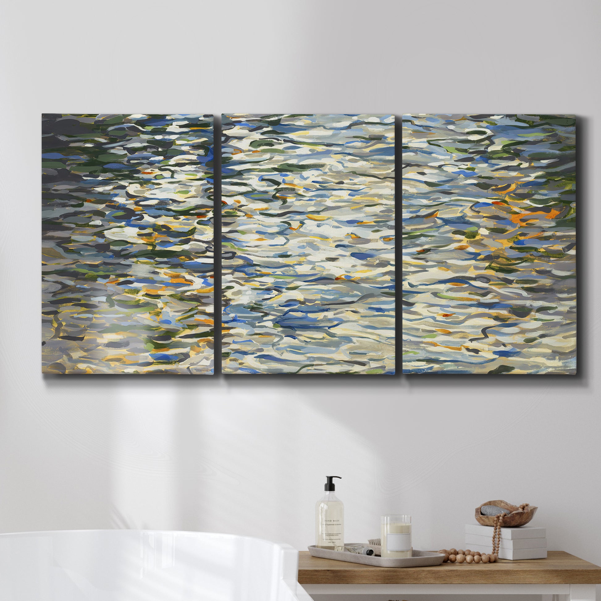 Three-panel canvas wall art featuring abstract water surface reflections, displayed in a bathroom above a bathtub.