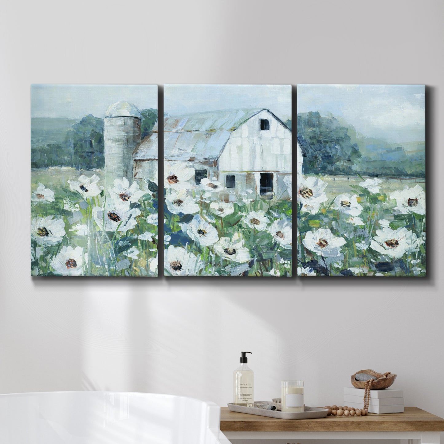 Three-panel canvas wall art featuring pastoral farmland with open fields, displayed in a bathroom above a bathtub.