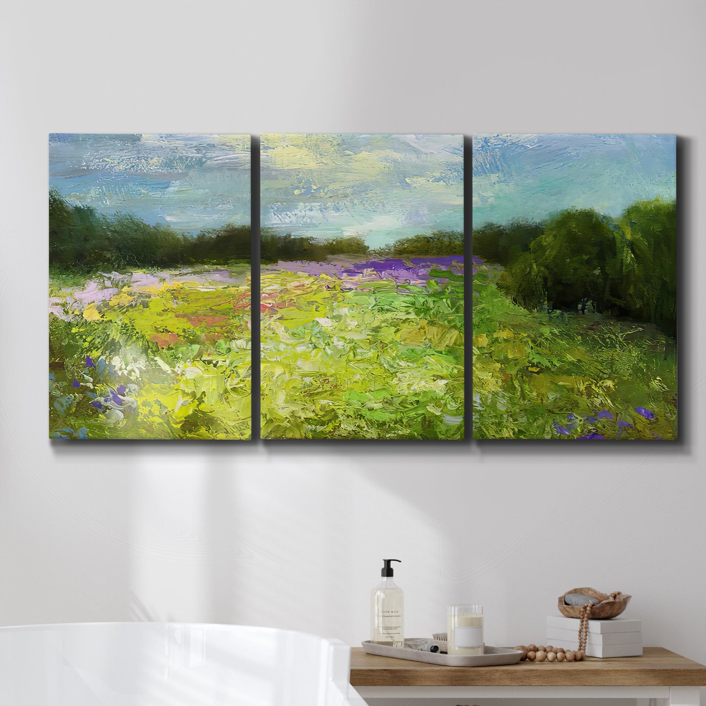Three-panel canvas wall art featuring pastoral field with wildflowers, displayed in a bathroom above a bathtub.