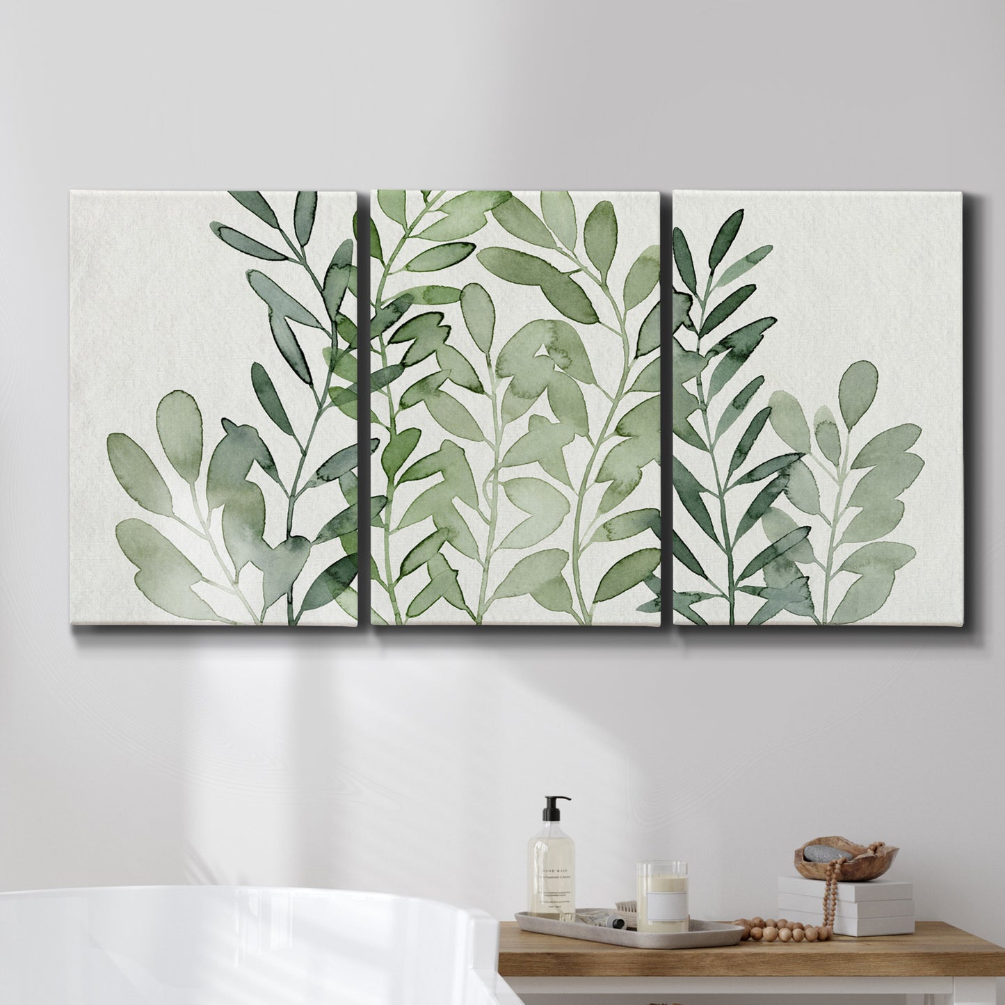 Three-panel canvas wall art featuring foraged leafy greens botanical study, displayed in a bathroom above a bathtub.