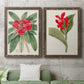 Set of two walnut barnwood framed canvas prints depicting a coordinated art pair of vivid tropical flowering plants rendered as antique botanical plate illustrations above a sofa in a modern living room.