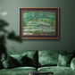 Impressionist garden scene with Japanese bridge and water lilies by Claude Monet in an ornate bronzed mahogany wood frame displayed in a dark-toned interior setting.