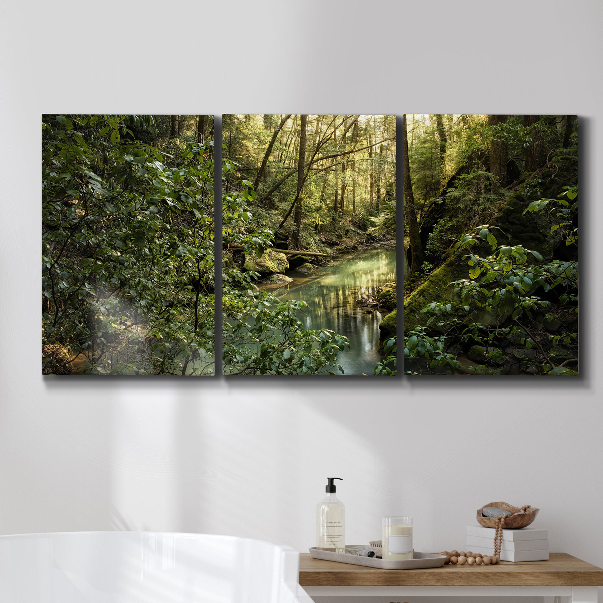 Three-panel canvas wall art featuring sun filtered woodland photograph, displayed in a bathroom above a bathtub.