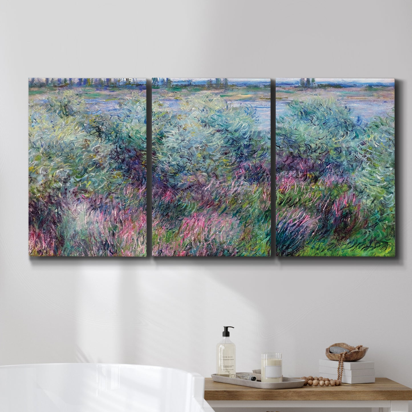 Three-panel canvas wall art featuring flowered riverbank with trees, displayed in a bathroom above a bathtub.