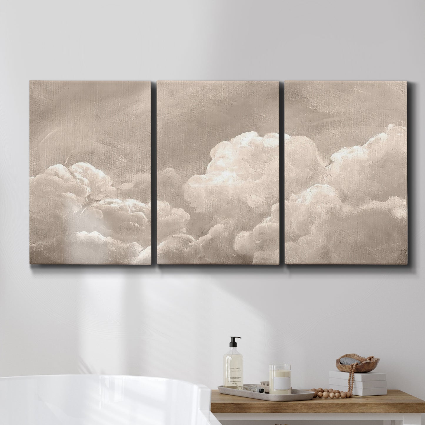 Three-panel canvas wall art featuring soft whimsical cloudscape, displayed in a bathroom above a bathtub.