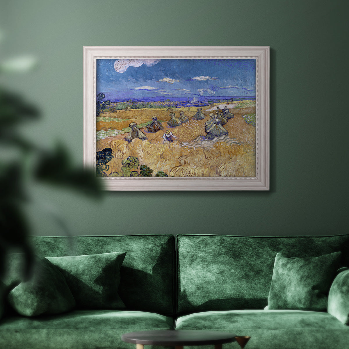 Impressionist wheat harvest scene by Vincent van Gogh in an ornate weathered white frame displayed in a dark-toned interior setting.