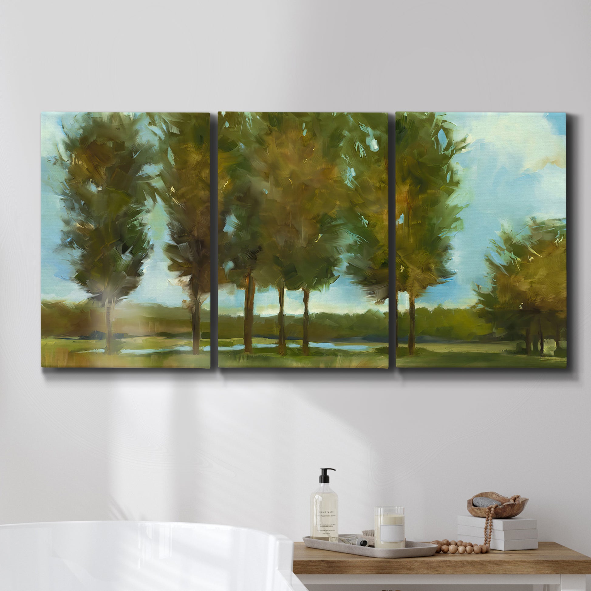 Three-panel canvas wall art featuring tall trees lining open landscape, displayed in a bathroom above a bathtub.