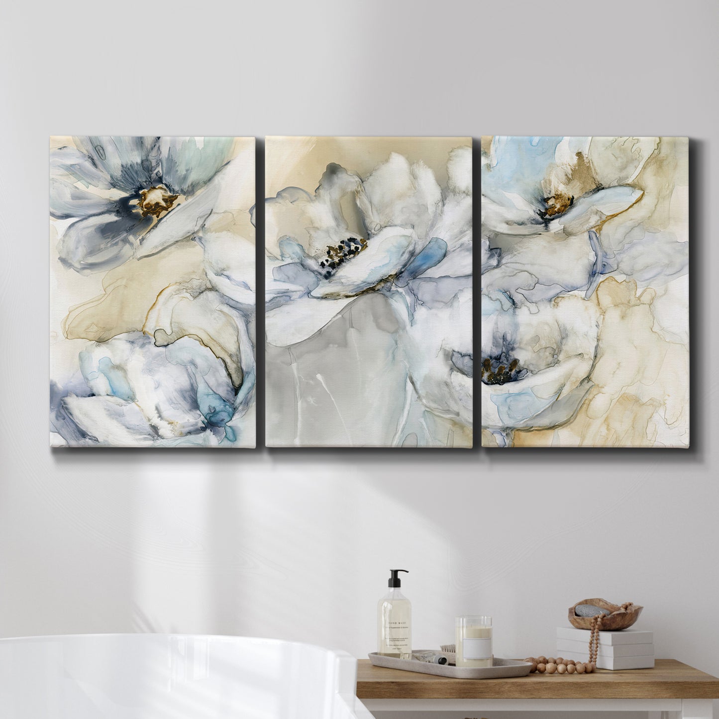 Three-panel canvas wall art featuring delicate watercolor floral blooms, displayed in a bathroom above a bathtub.