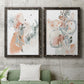 Set of two black barnwood framed canvas prints depicting a coordinated art pair of loose blush gray and coral floral gestures rendered as abstract watercolor botanicals above a sofa in a modern living room.