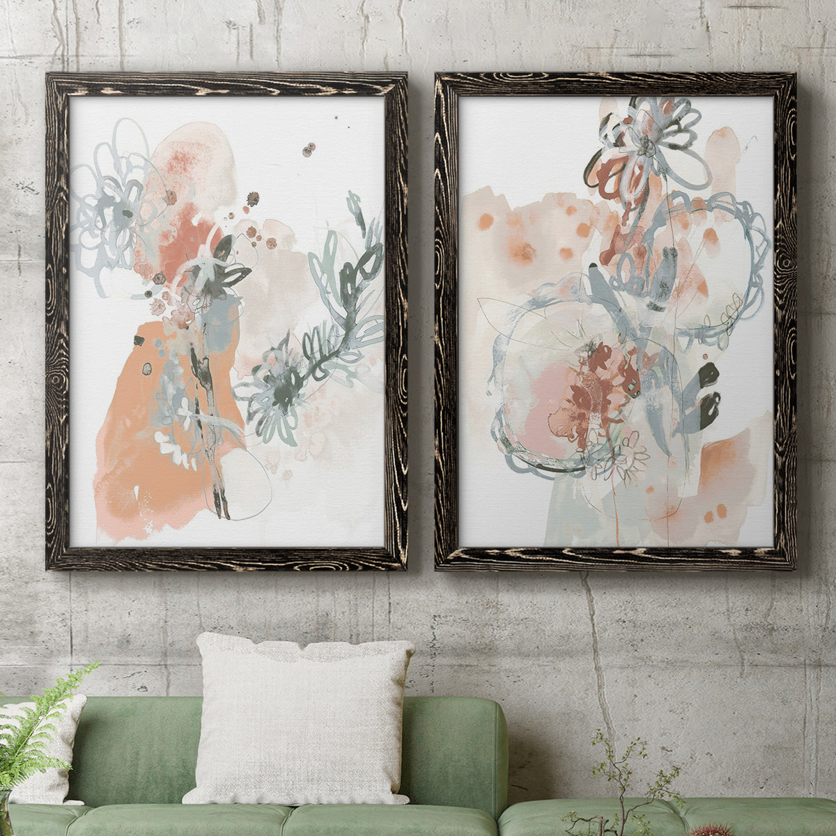 Set of two black barnwood framed canvas prints depicting a coordinated art pair of loose blush gray and coral floral gestures rendered as abstract watercolor botanicals above a sofa in a modern living room.