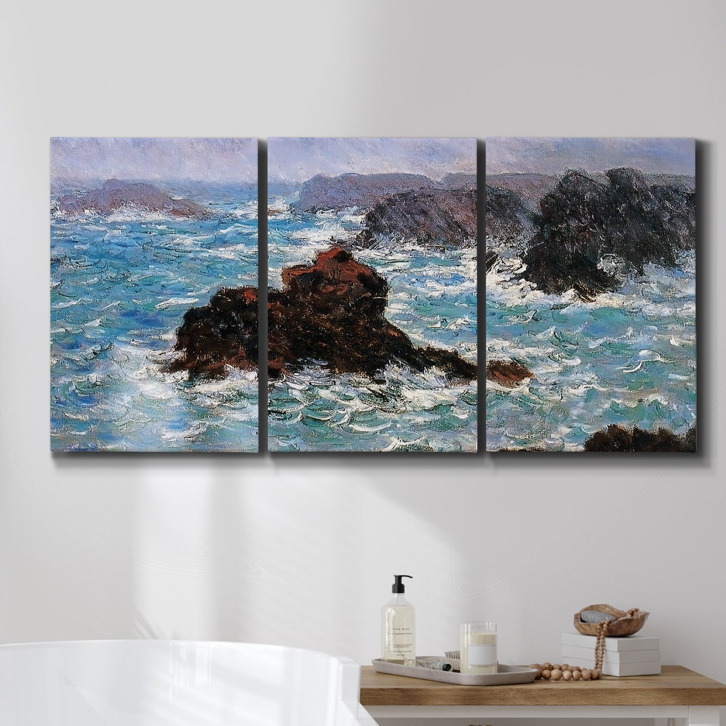 Three-panel canvas wall art featuring storm waves battering rocky coast, displayed in a bathroom above a bathtub.