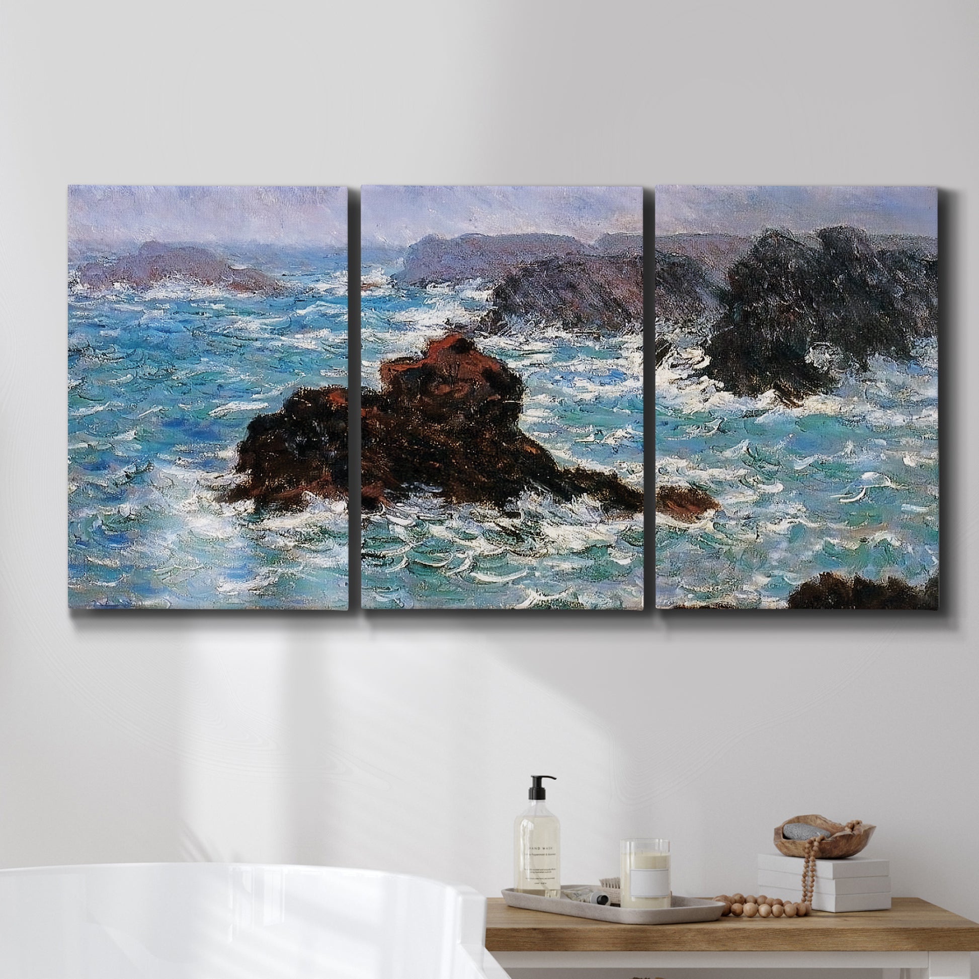 Three-panel canvas wall art featuring storm waves battering rocky coast, displayed in a bathroom above a bathtub.