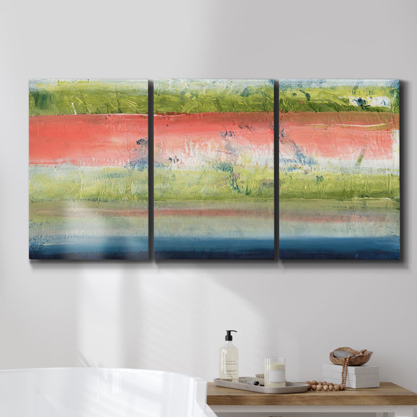 Three-panel canvas wall art featuring layered abstract color banding, displayed in a bathroom above a bathtub.