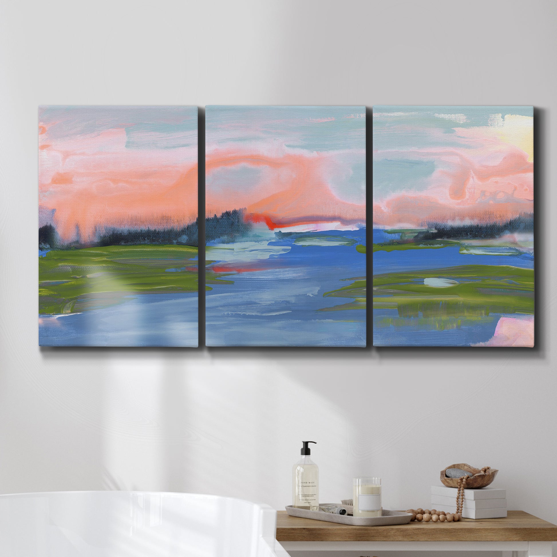 Three-panel canvas wall art featuring sunset reflections across calm sea, displayed in a bathroom above a bathtub.