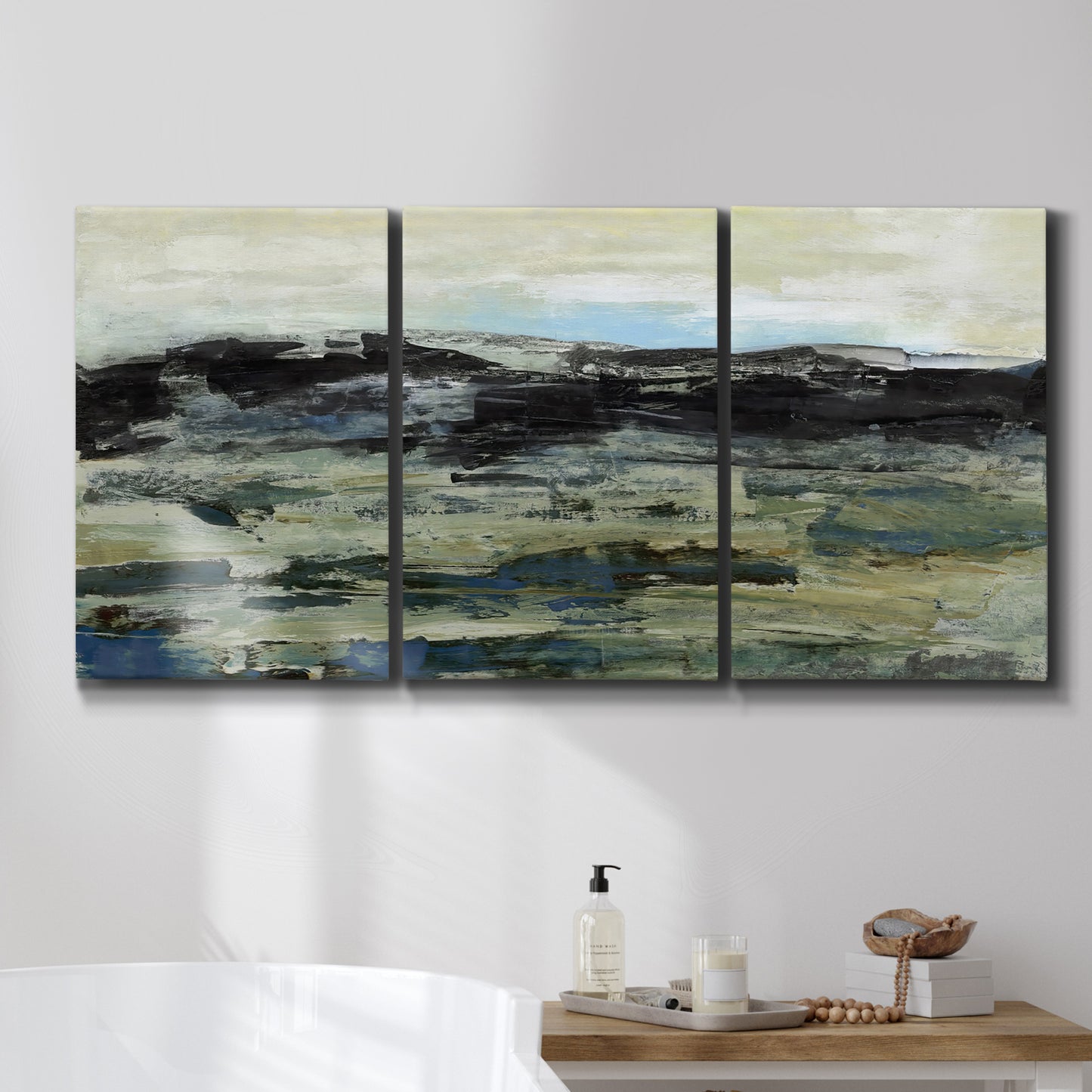 Three-panel canvas wall art featuring muted abstract landscape study, displayed in a bathroom above a bathtub.