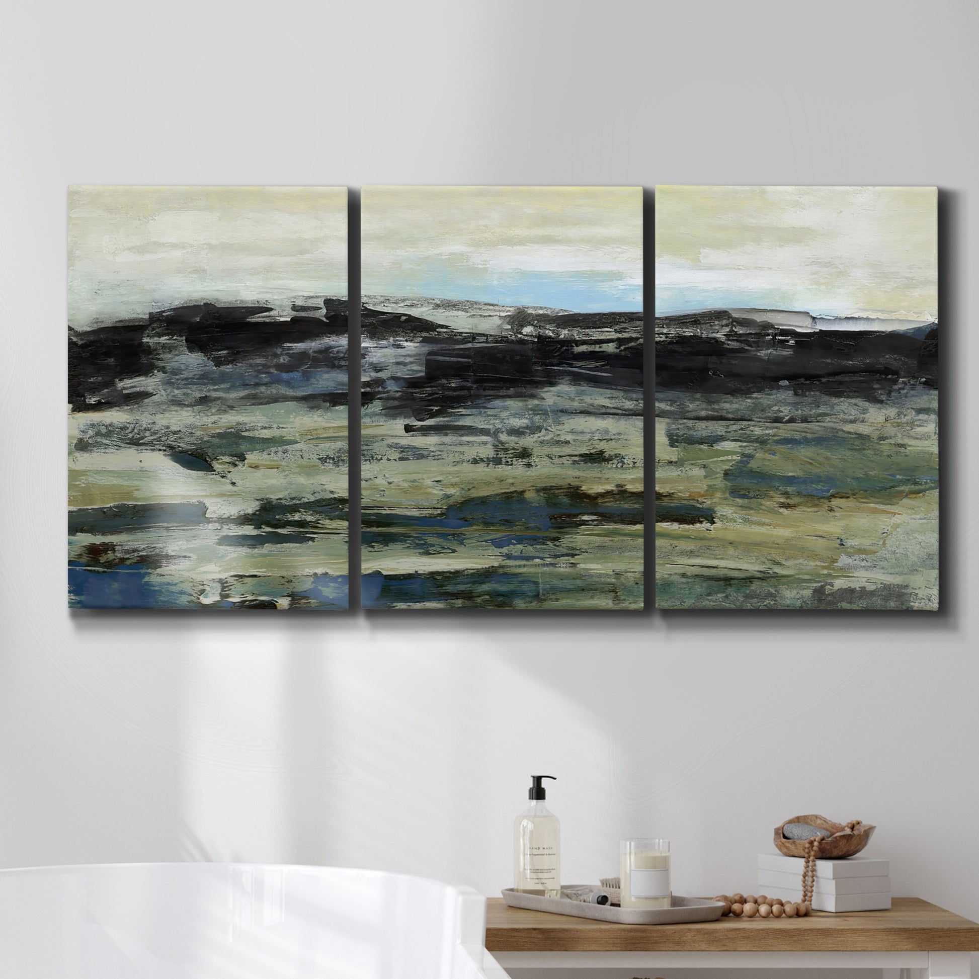 Three-panel canvas wall art featuring muted abstract landscape study, displayed in a bathroom above a bathtub.