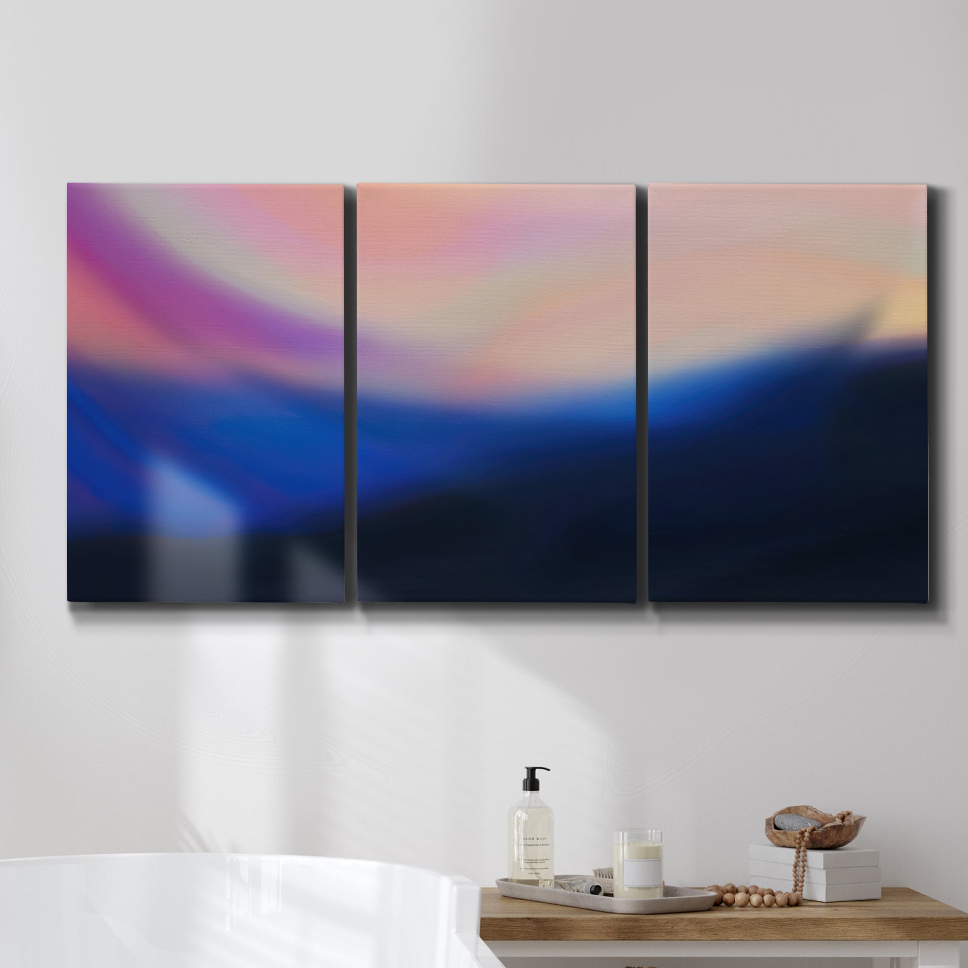 Three-panel canvas wall art featuring smooth abstract sunset color gradient, displayed in a bathroom above a bathtub.