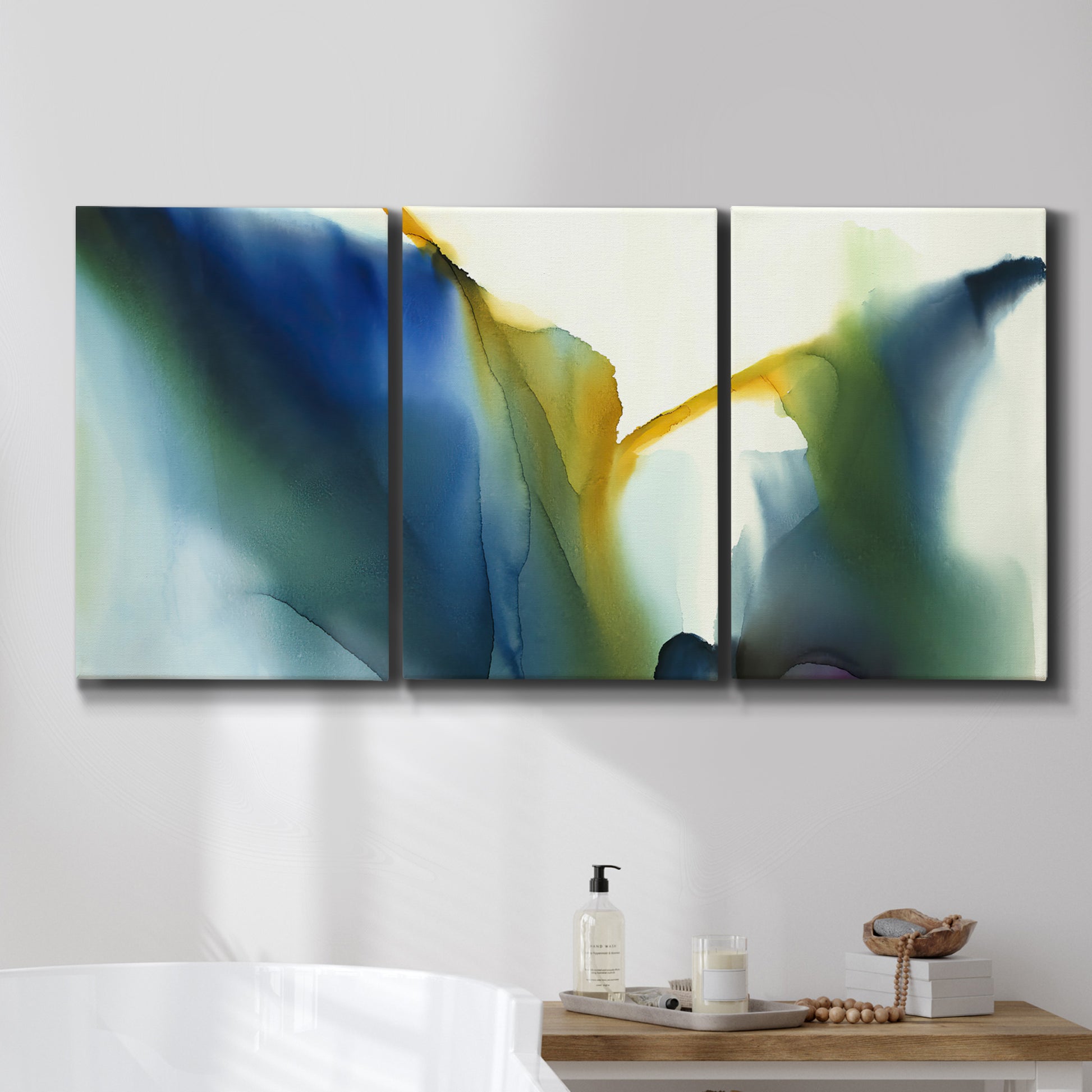Three-panel canvas wall art featuring soft abstract mask like forms, displayed in a bathroom above a bathtub.