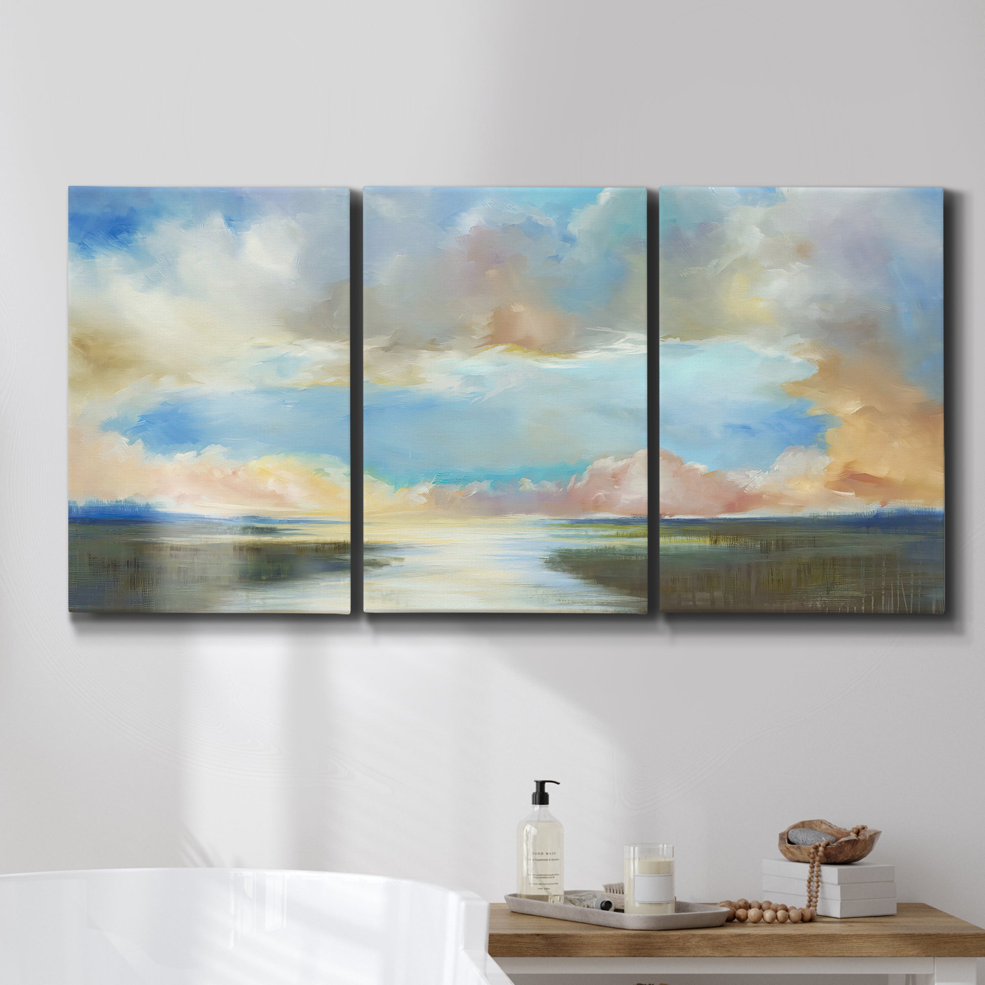 Three-panel canvas wall art featuring dawn light breaking over water, displayed in a bathroom above a bathtub.