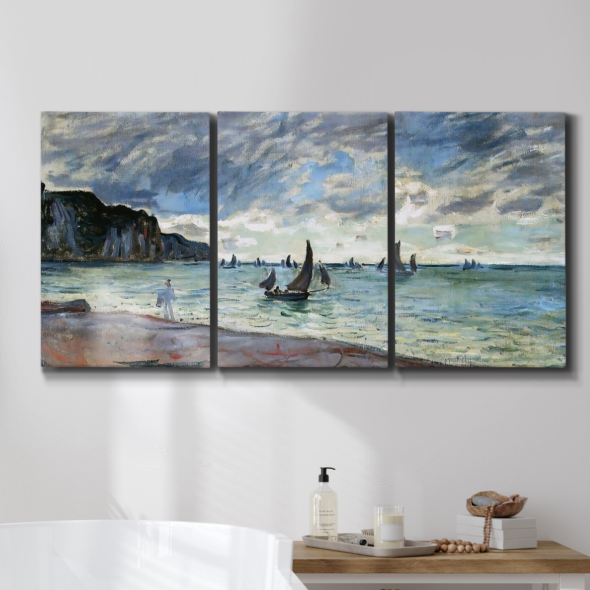 Three-panel canvas wall art featuring figures walking along sandy shoreline, displayed in a bathroom above a bathtub.