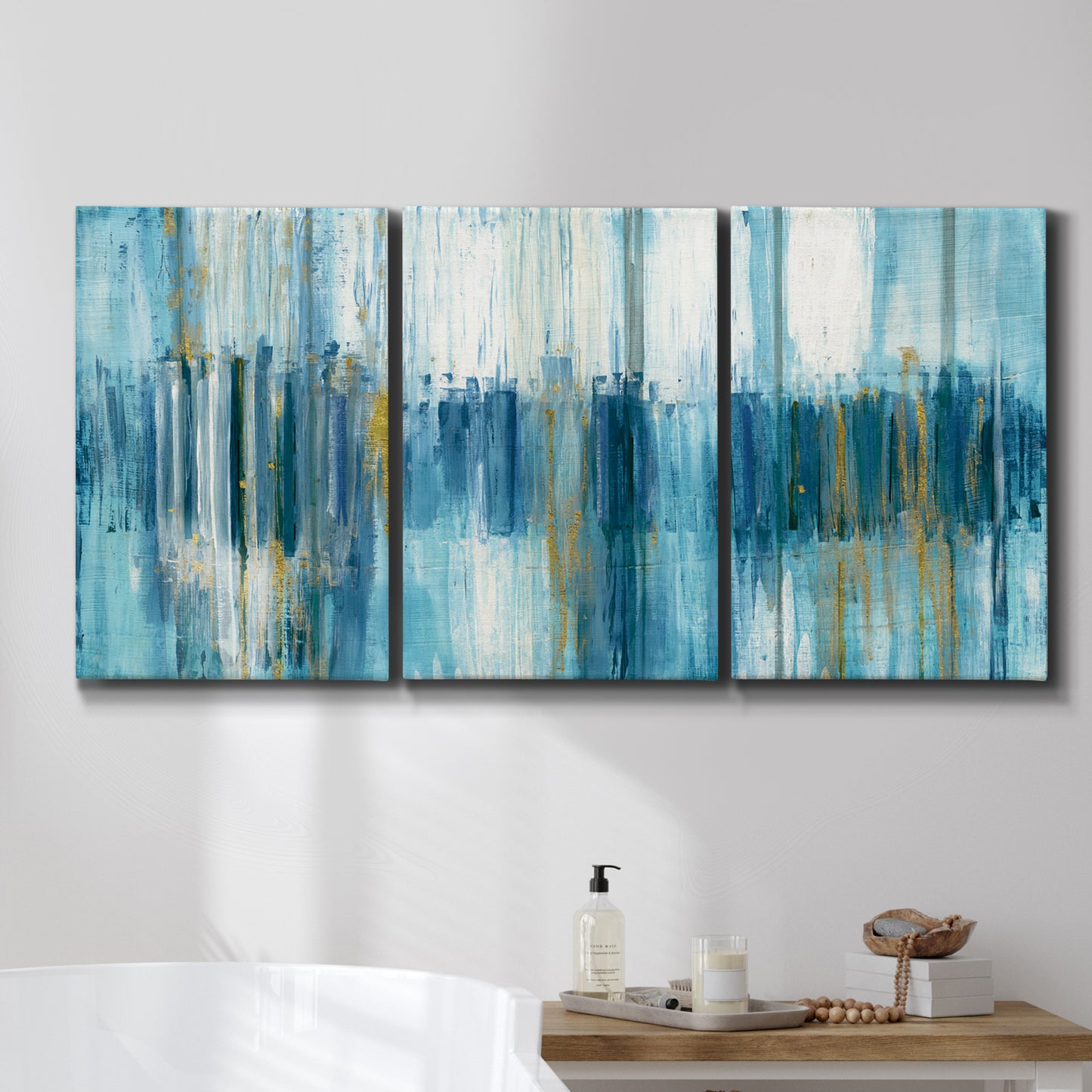 Three-panel canvas wall art featuring layered abstract earth tones, displayed in a bathroom above a bathtub.