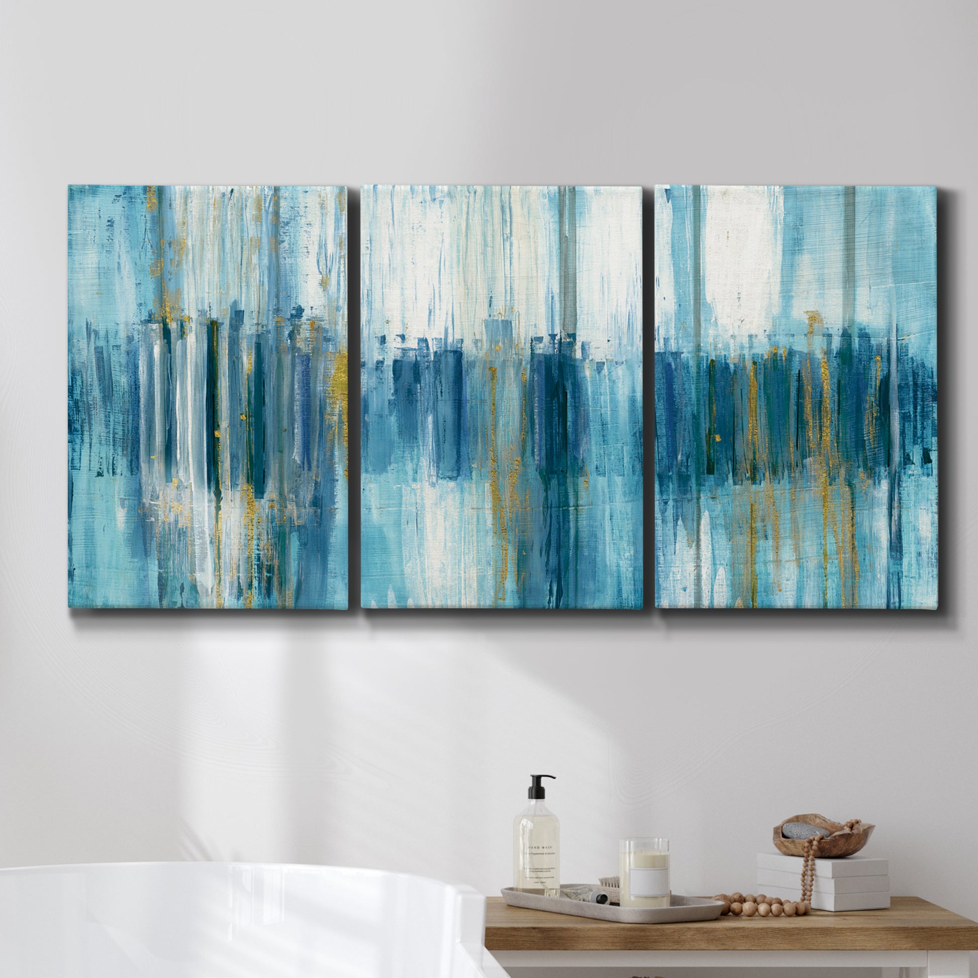 Three-panel canvas wall art featuring layered abstract earth tones, displayed in a bathroom above a bathtub.