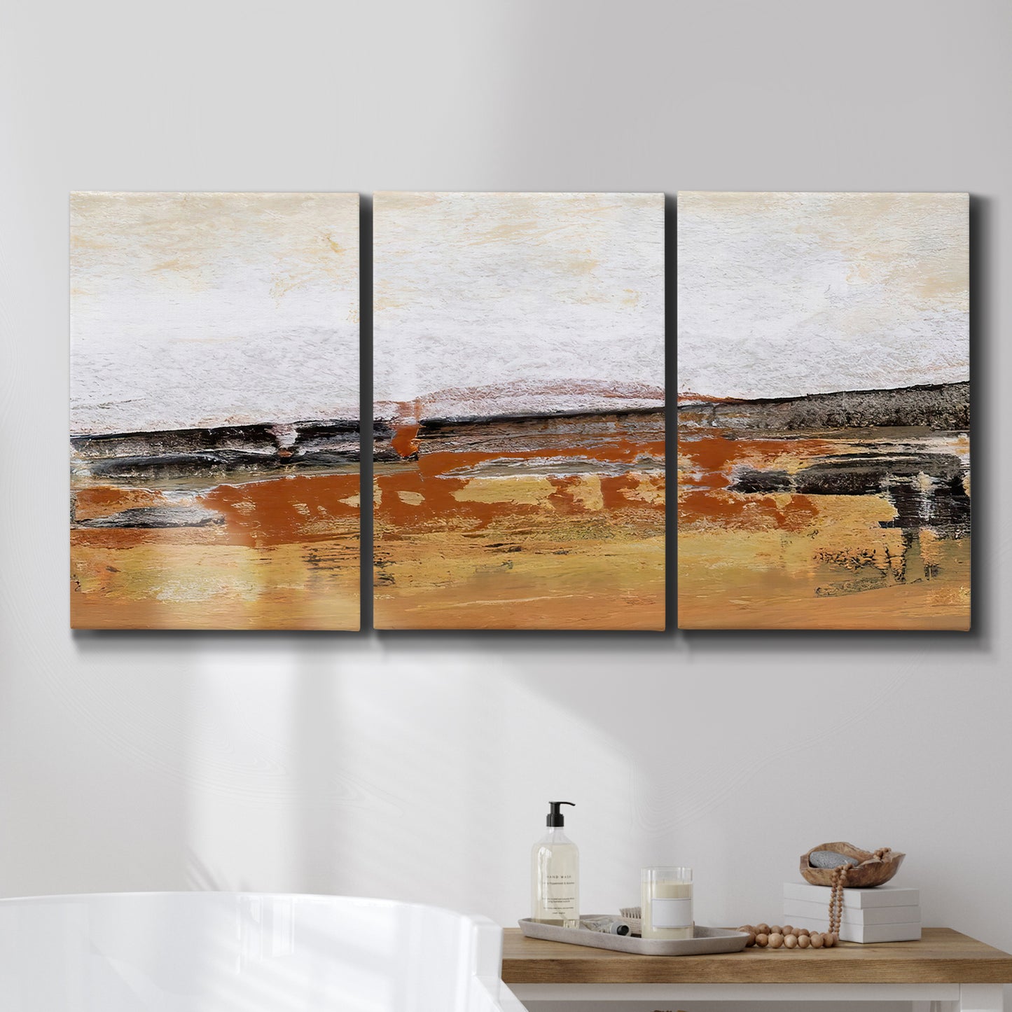 Three-panel canvas wall art featuring abstract bridge landscape in ochre, displayed in a bathroom above a bathtub.