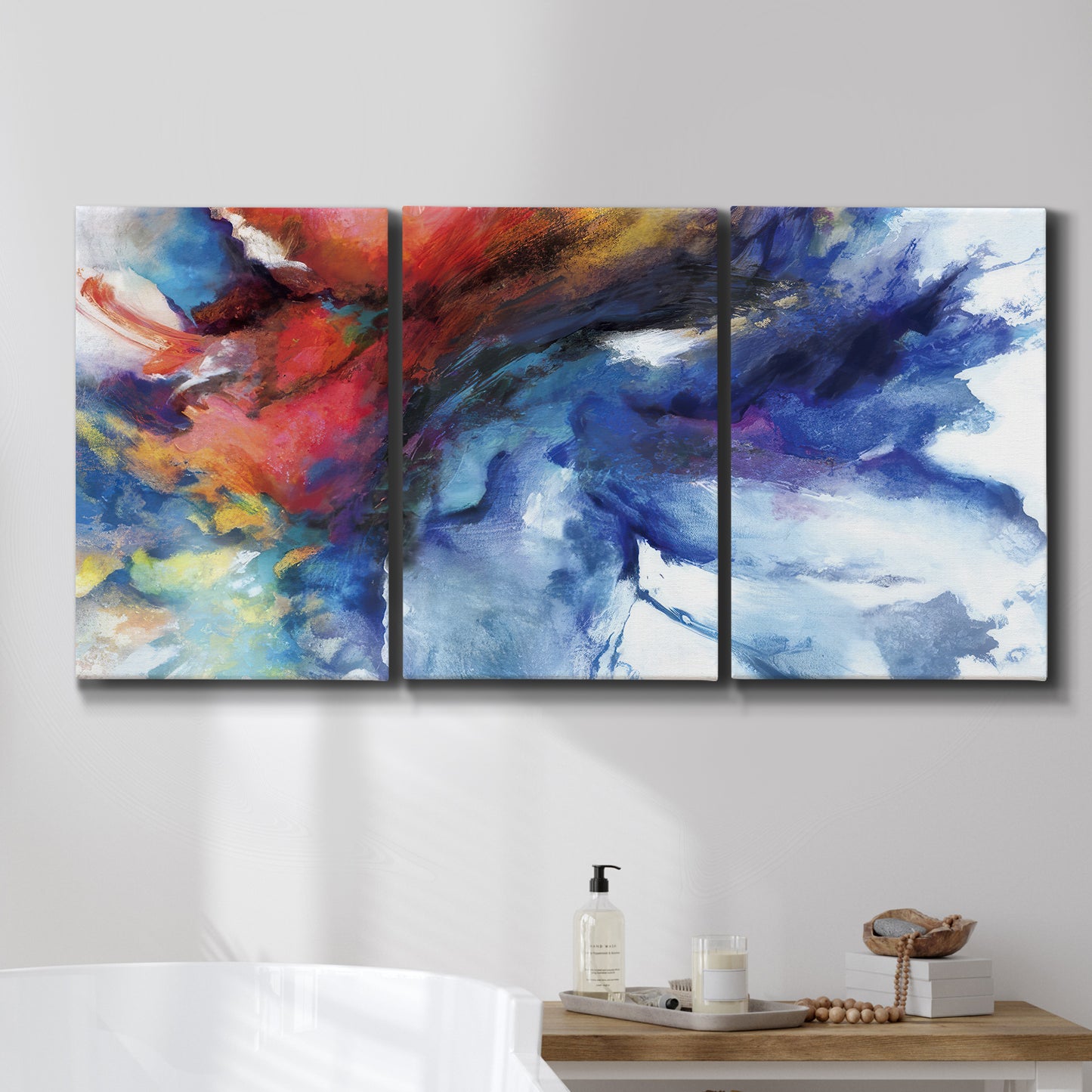 Three-panel canvas wall art featuring vibrant abstract color explosion, displayed in a bathroom above a bathtub.