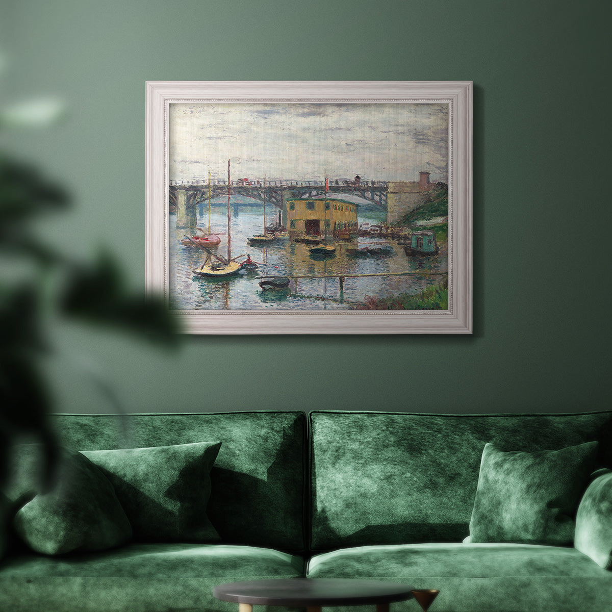 Impressionist river bridge scene on an overcast day by Claude Monet in an ornate weathered white frame displayed in a dark-toned interior setting.