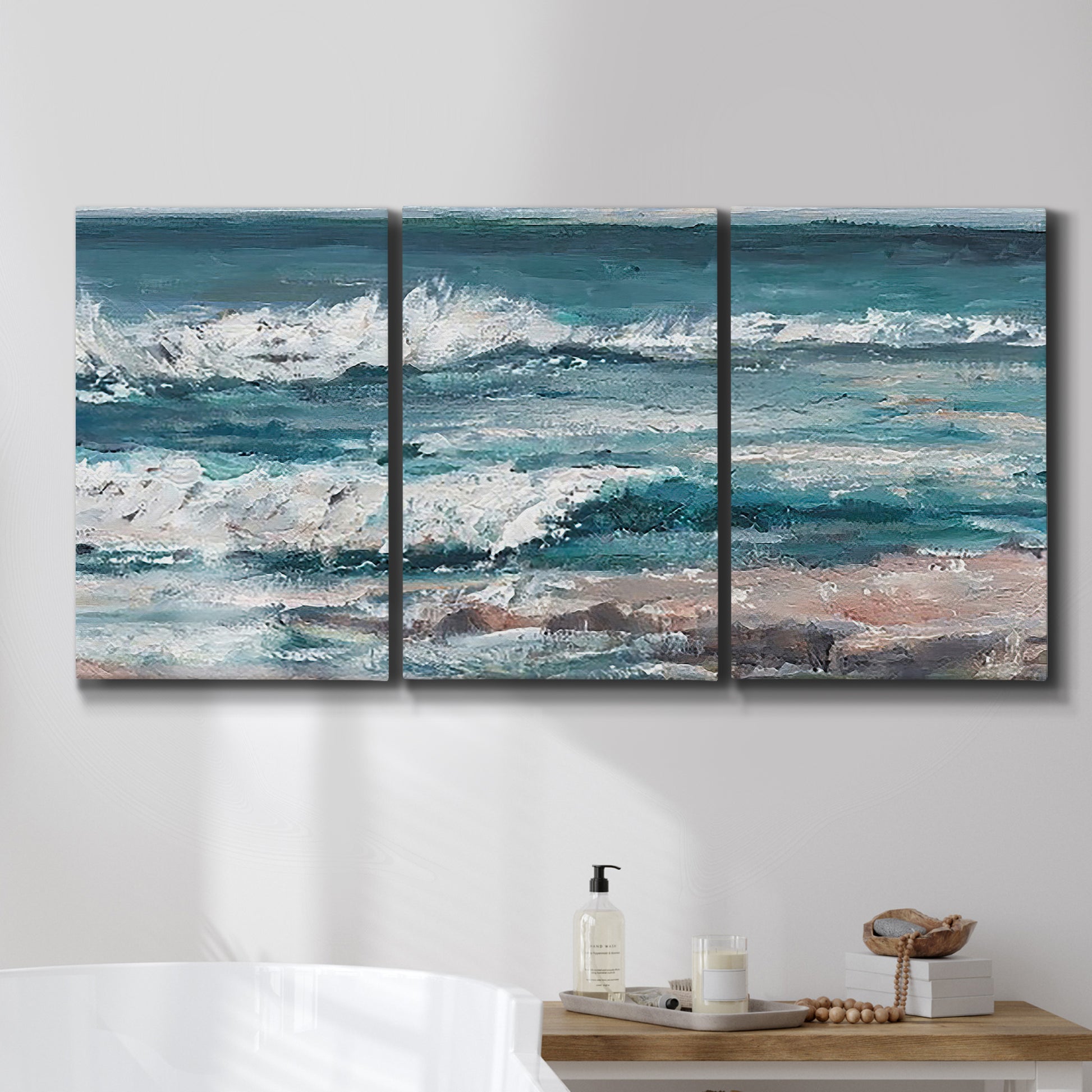 Three-panel canvas wall art featuring crashing ocean waves along shoreline, displayed in a bathroom above a bathtub.