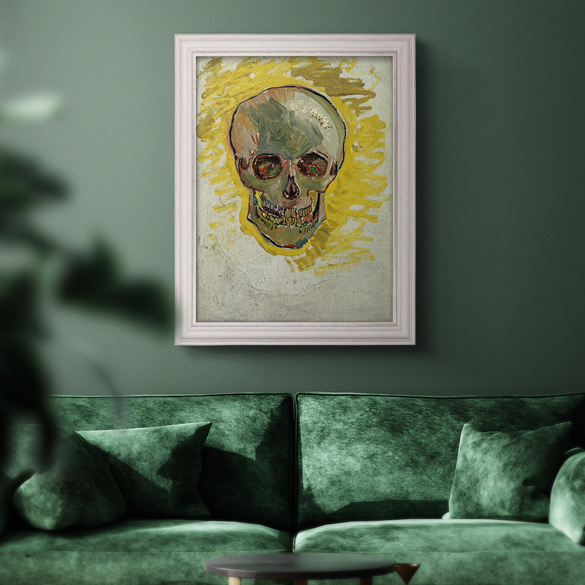 Expressive skull study painting by Vincent van Gogh in an ornate weathered white frame displayed in a dark-toned interior setting.