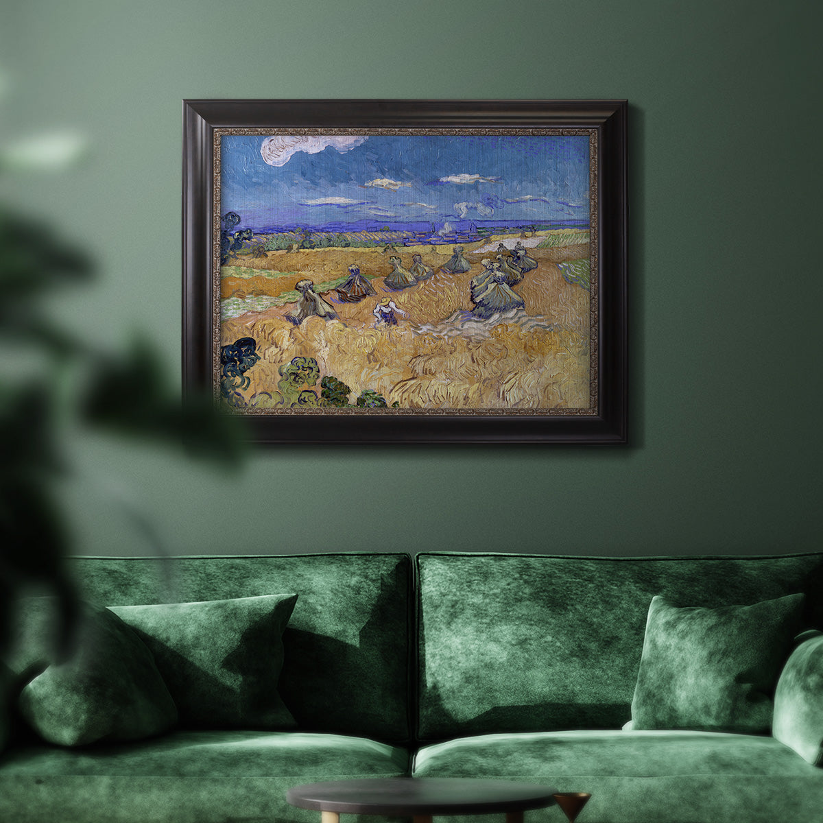 Impressionist wheat harvest scene by Vincent van Gogh in an ornate black frame with gilded inner detail displayed in a dark-toned interior setting.