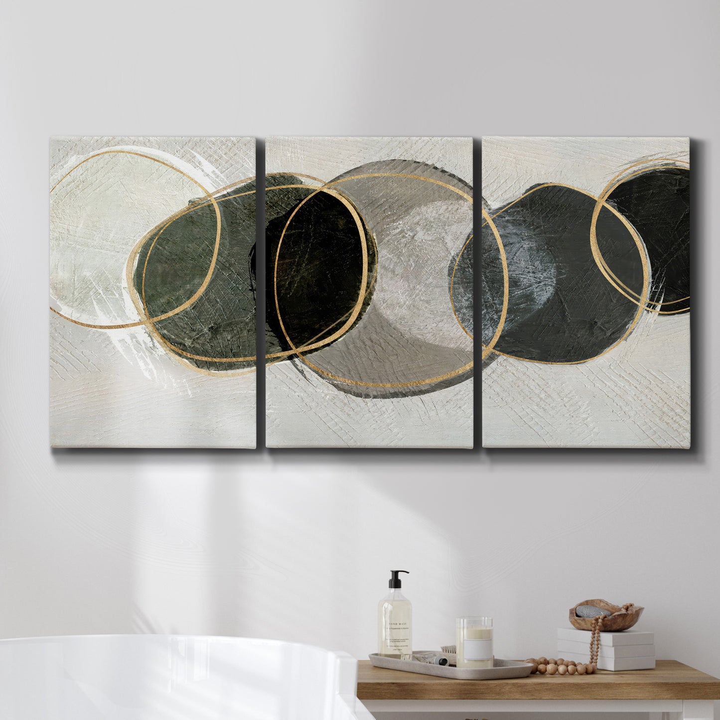 Three-panel canvas wall art featuring smooth abstract river stone forms, displayed in a bathroom above a bathtub.