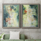 Set of two gray barnwood framed canvas prints depicting a coordinated art pair of layered blue green cream and charcoal textures rendered as nature-inspired mixed-media abstracts above a sofa in a modern living room.