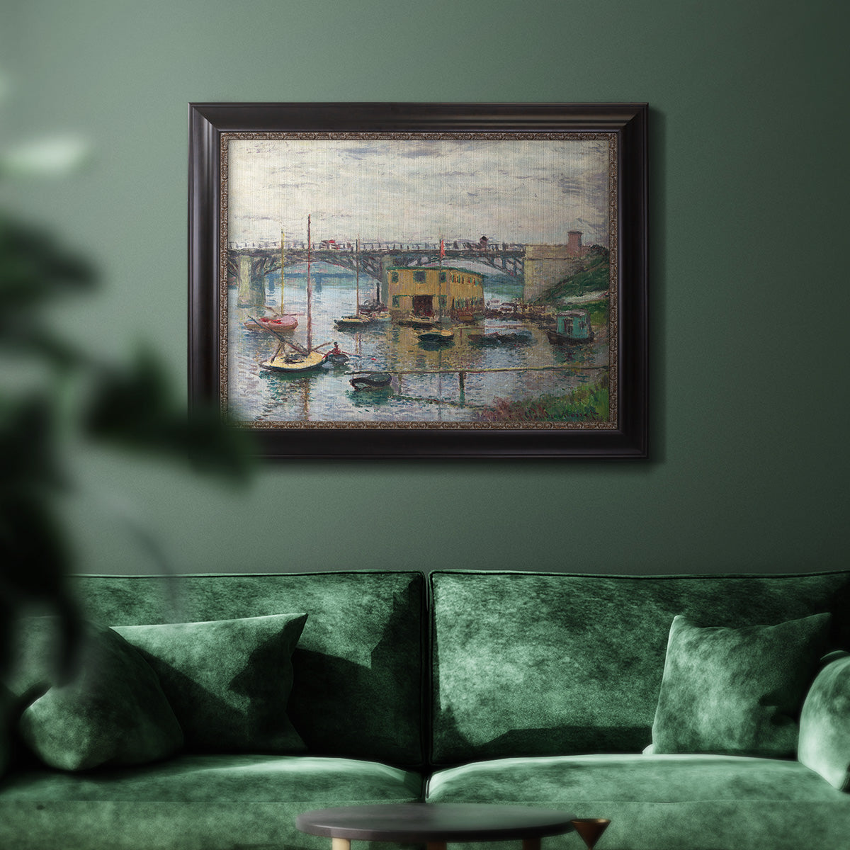 Impressionist river bridge scene on an overcast day by Claude Monet in an ornate black frame with gilded inner detail displayed in a dark-toned interior setting.