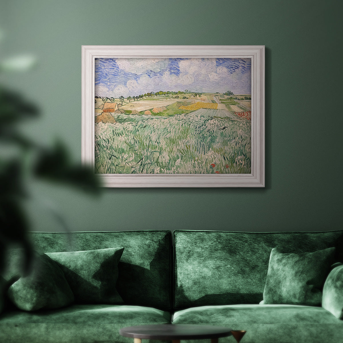 Impressionist countryside landscape near Auvers by Vincent van Gogh in an ornate weathered white frame displayed in a dark-toned interior setting.