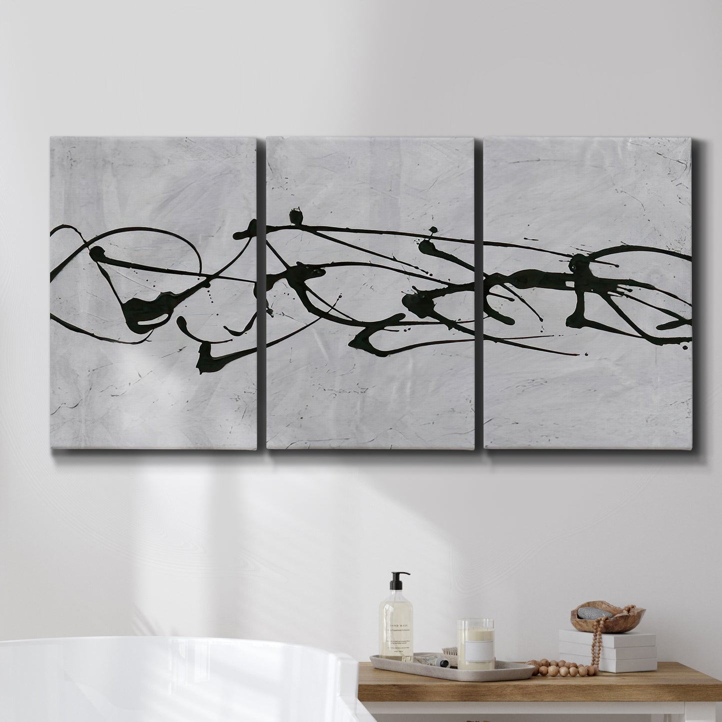 Three-panel canvas wall art featuring minimal abstract frequency lines, displayed in a bathroom above a bathtub.