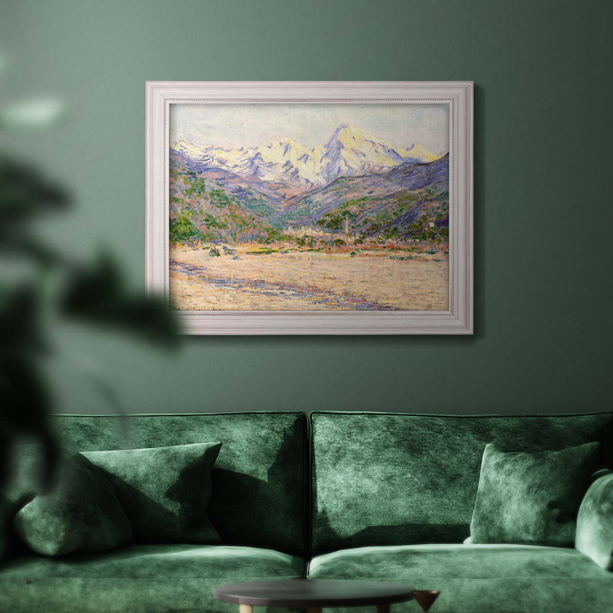 Impressionist valley landscape in southern France by Claude Monet in an ornate weathered white frame displayed in a dark-toned interior setting.