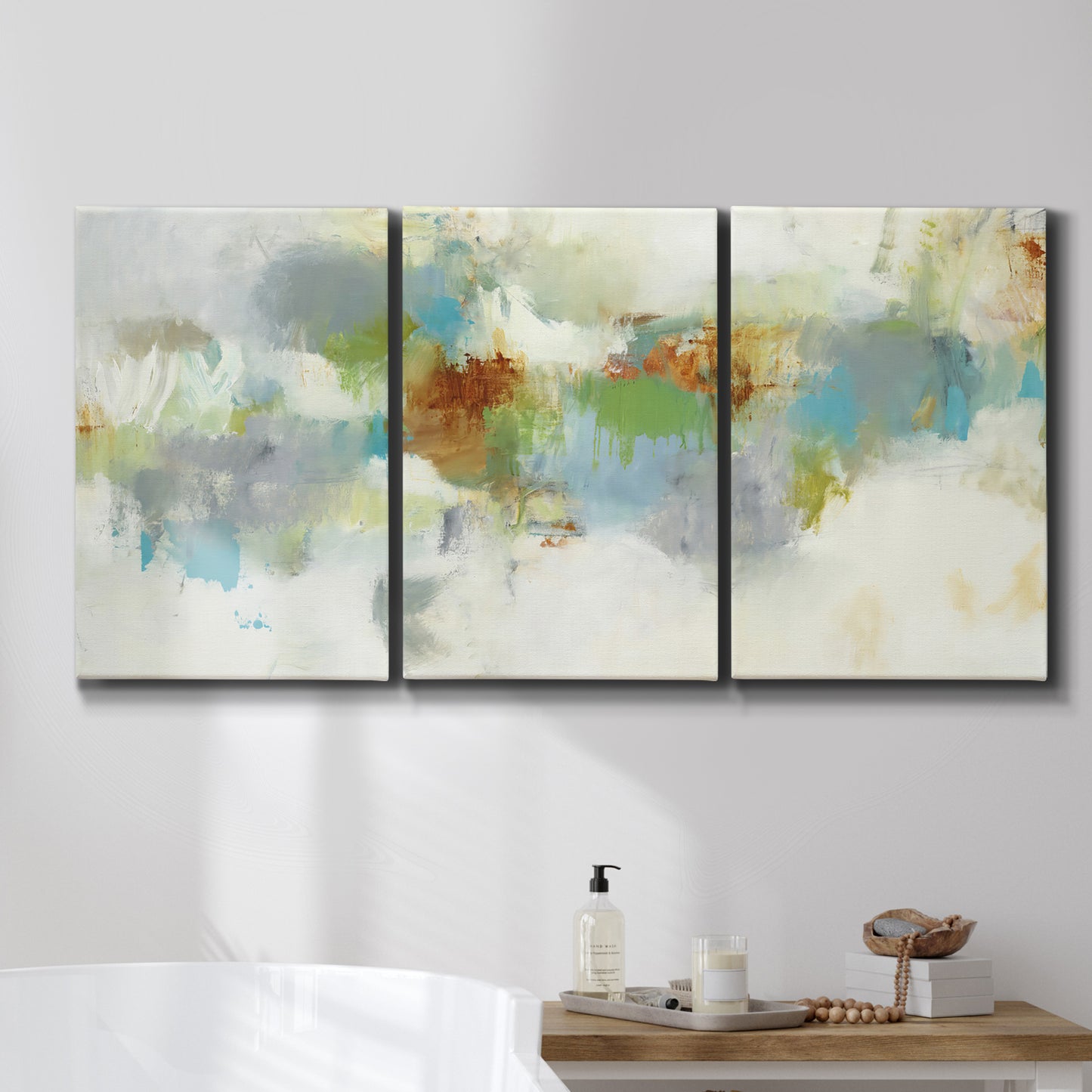 Three-panel canvas wall art featuring abstract suggestion of discovery, displayed in a bathroom above a bathtub.