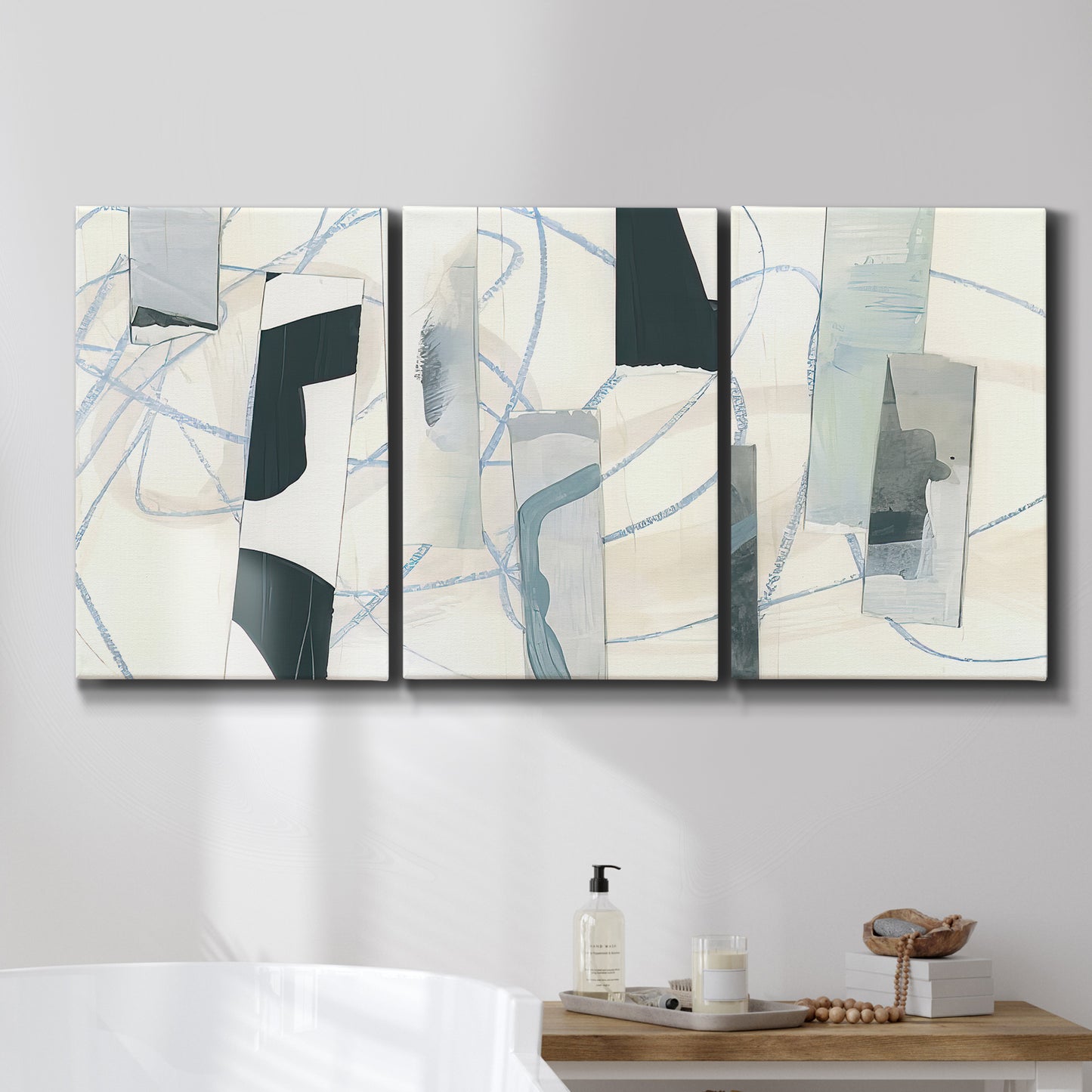 Three-panel canvas wall art featuring interwoven icy abstract linear forms, displayed in a bathroom above a bathtub.