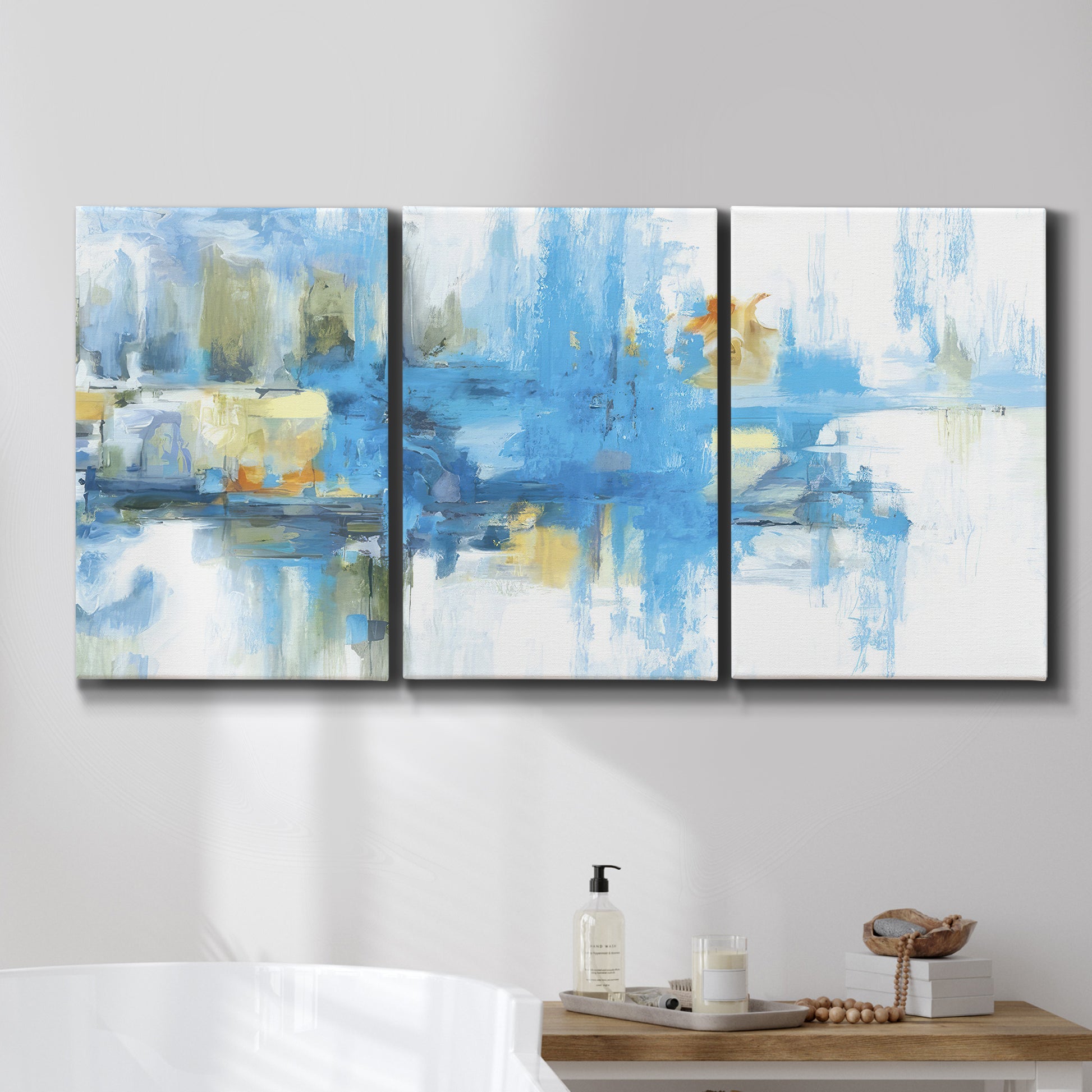 Three-panel canvas wall art featuring blue toned abstract city rhythm, displayed in a bathroom above a bathtub.